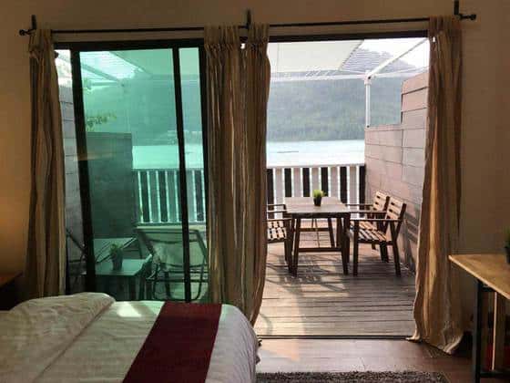 停泊岛巴拉特停泊岛度假村海景小屋宽敞的阳台配有两把躺椅四把木椅和一张支架桌