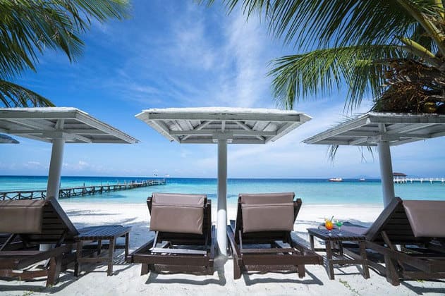 浪中岛夏日海湾度假村海滩前的遮阳伞下的沙滩椅