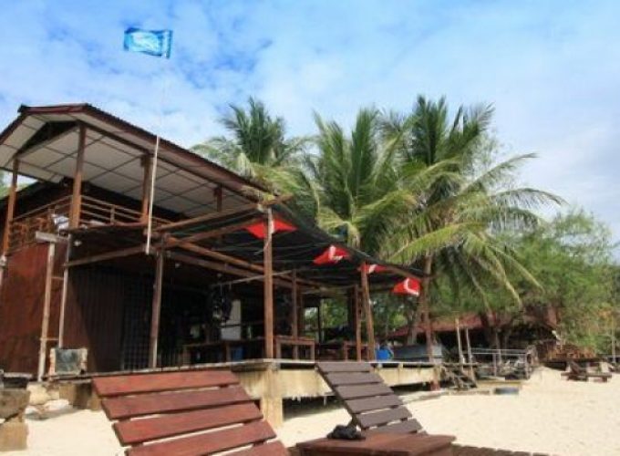 two wooden deck chairs on beach in front of redang pelangi resort