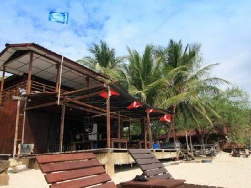 two wooden deck chairs on beach in front of redang pelangi resort