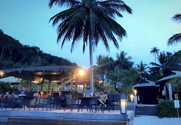 热浪岛晚上有一个男人坐在度假村户外餐厅的椅子上放松