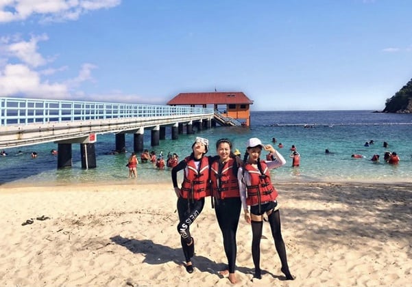 three women standing on Redang Marine Park beach wearing life jacket