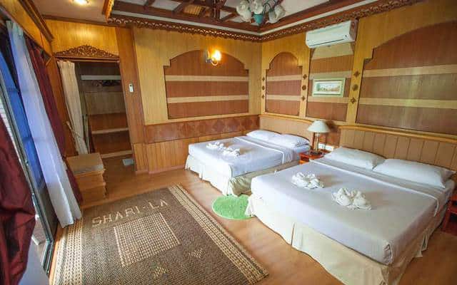 停泊岛莎丽拉度假村的木制房间内部配有两张双人床