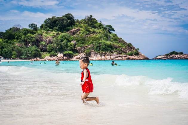 热浪岛穿红衬衫的男孩在海滩上快乐地奔跑
