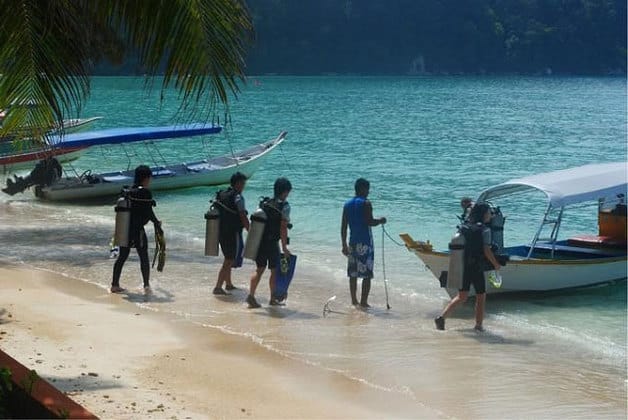 停泊岛人们拿着潜水装备步行到海边登上快艇进行潜水之旅