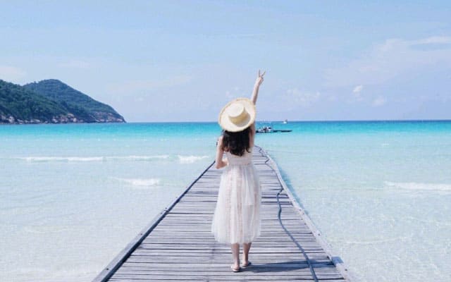 停泊岛身着白色连衣裙的女人站在清澈湛蓝的海水上方的码头