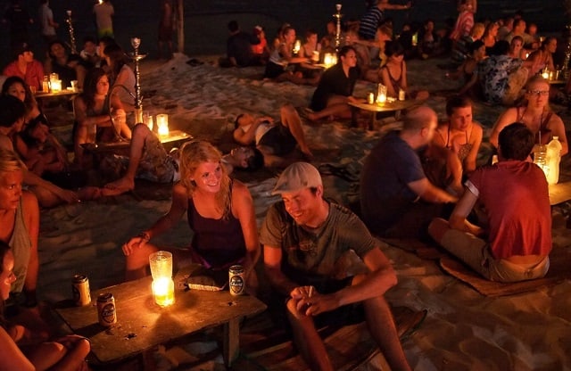 停泊岛晚上的海滩上游客们围坐在带烛光的小桌子旁放松 