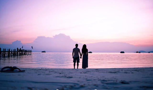 停泊岛一对情侣站在海滩欣赏日落 