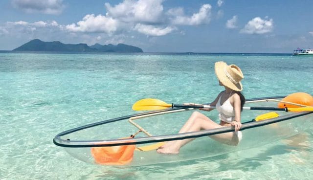 停泊岛清澈的海面上有位戴草帽的女人坐在玻璃皮艇