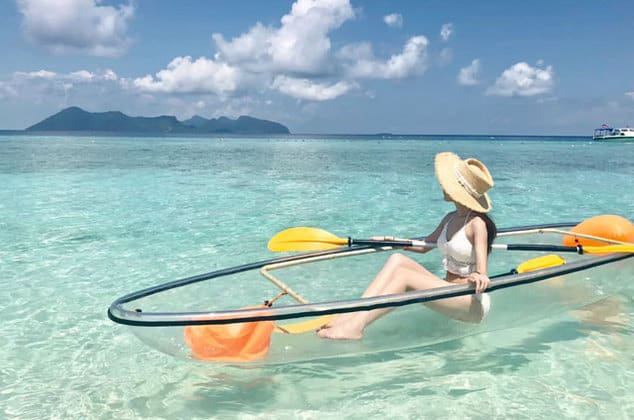 woman in straw hat sitting on glass kayak above clear sea of perhentian island