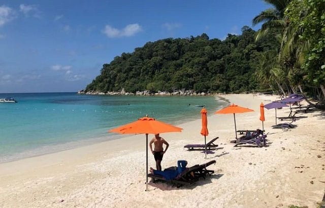 停泊岛游客站在海滩橙色沙滩伞下乘凉
