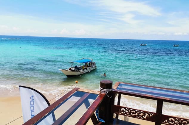 empty trestle bench on pulau tioman island beach while speedboat resting at shore