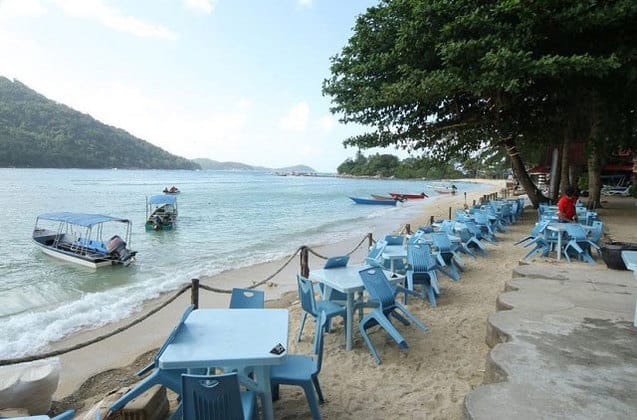 停泊岛海滩围栏外的塑料桌椅 