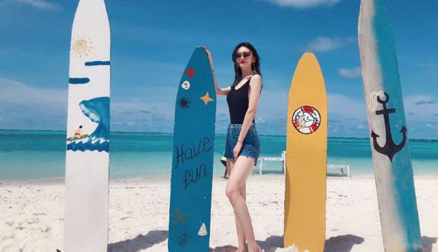停泊岛海滩上站着一个女人拿着五颜六色的冲浪板