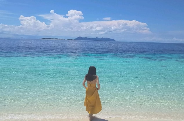 停泊岛海滩上站着一个女人身穿黄色连衣裙