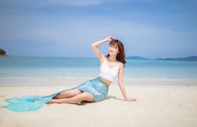 woman with mermaid tail costume sitting on redang island sandy beach in a sunny day