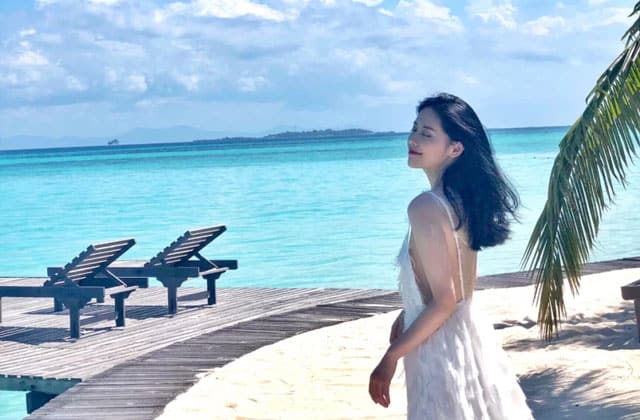 girl in black hair and white dress standing on beach of sibu island