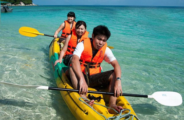 three tourists playing banana boat on kapas island sea water