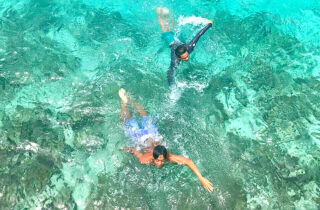 two men swimming in sibu island clear sea water