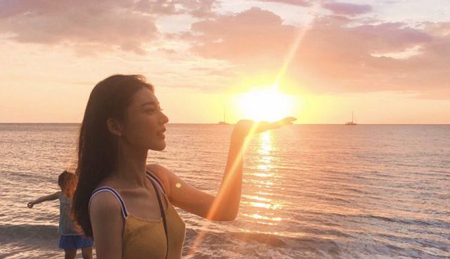 woman poses her palm with setting sun at sibu island beach