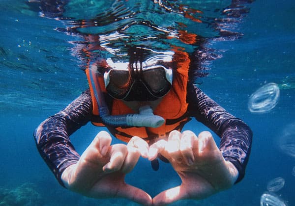 guest snorkeling at tinggi island clear sea showing love gesture by hands