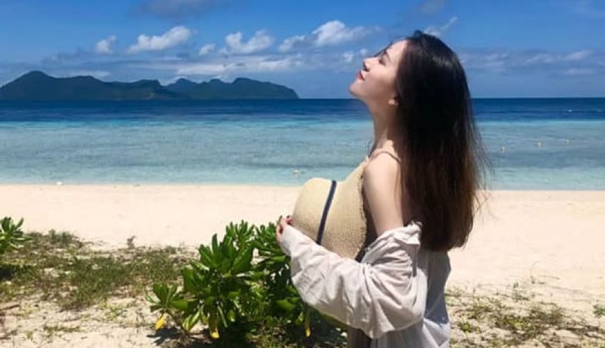 woman standing on beach of tinggi island looking into sky