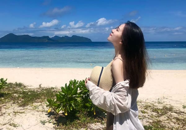 woman standing on beach of tinggi island looking into sky