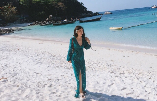 在帕芒吉尔岛海滩上行走的的女人身穿墨绿色的连衣裙
