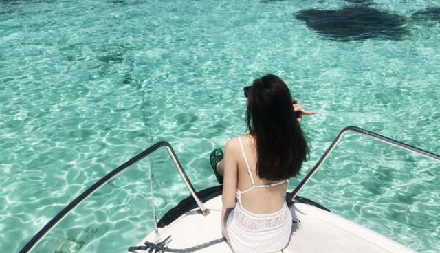 black hair woman in white dress sitting on yacht in tinggi island sea