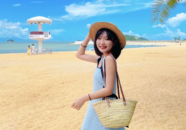 戴着草帽的女人站在沙滩上微笑