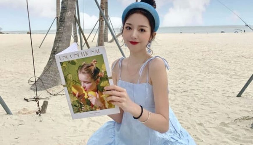 woman holding magazine sitting on beach of aur island