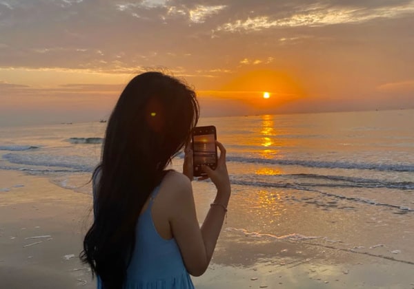 woman taking pictures of sunset in aur island beach