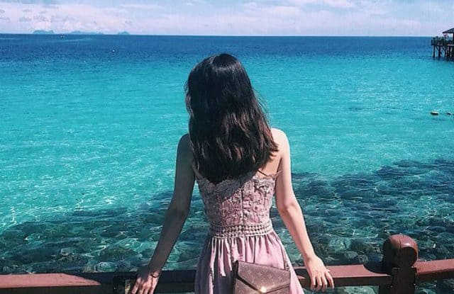 奥尔岛穿着粉红色连衣裙的女人看着湛蓝的大海
