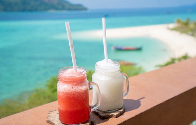 two cold smoothies resting on the banister of balcony with the koh lipe island seaview at back