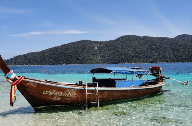 empty long tail boat resting on beach of koh lipe island