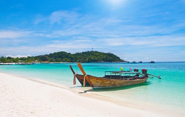长尾船在泰国丽贝岛清澈的蓝色海水海滩上停靠