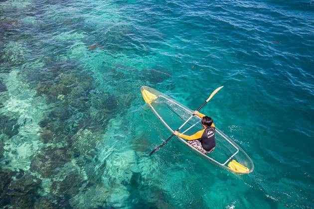 man rowing glass boat on clear seawater of mabul island