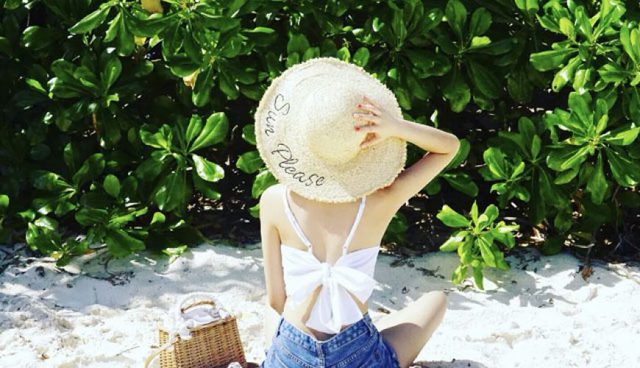 woman in straw hat sitting on beach of tenggol island