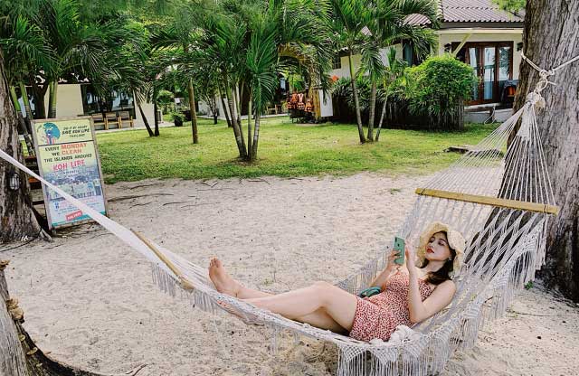 躺在泰国丽贝岛海滩吊床上戴草帽的女人